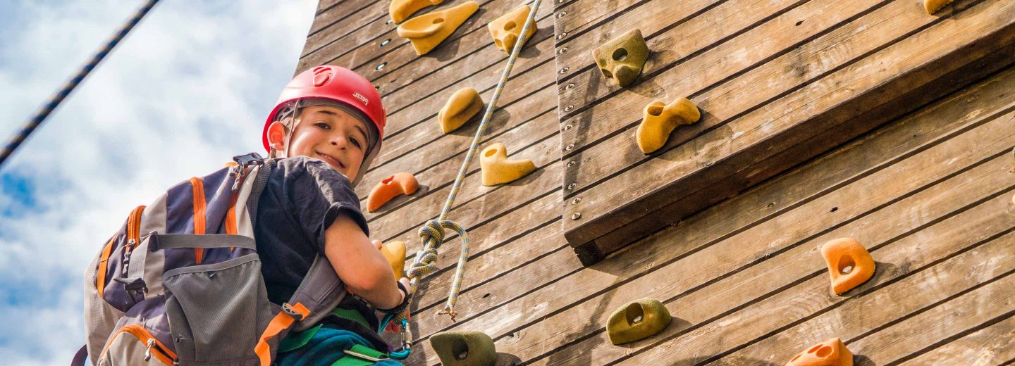 Boy on rock climbing wall with backpack