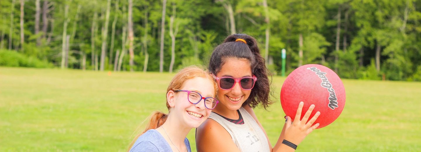 Girl campers with dodgeball outside