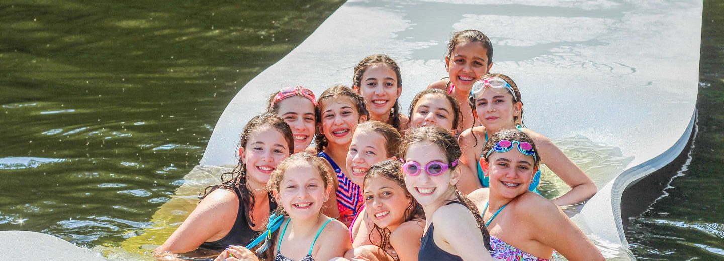 Girl campers on floating mat in lake