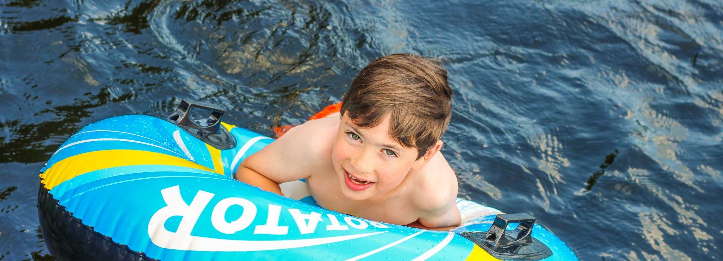 Boy camper in water on inflatable raft