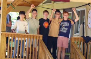 Group of students smiling and hanging out together on a deck.